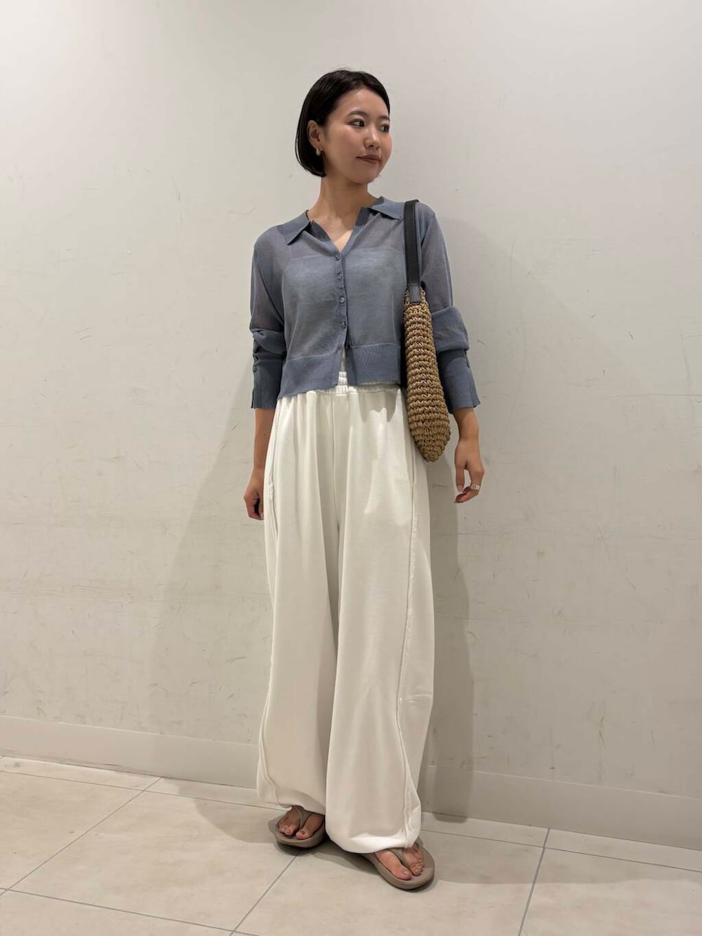 イエロー系のトートバッグ、ベージュ系のサンダル、ホワイト系のキャミソールを着用したレディースの夏コーディネートの2枚目の写真