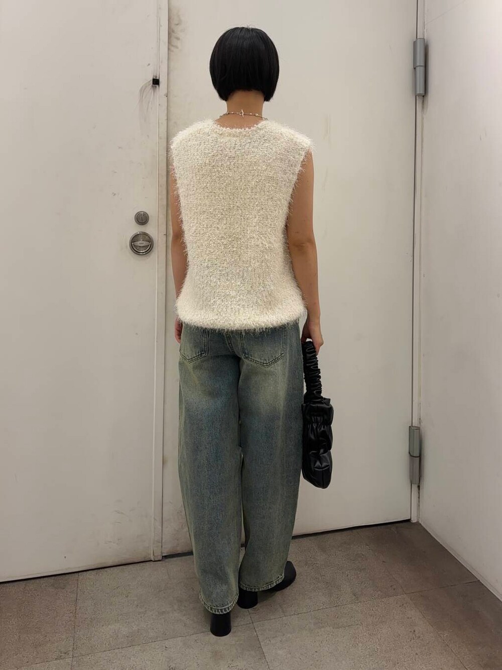 ブラック系のその他シューズ、ブラック系のハンドバッグ、ブルー系のデニムパンツを着用したレディースの秋コーディネートの4枚目の写真