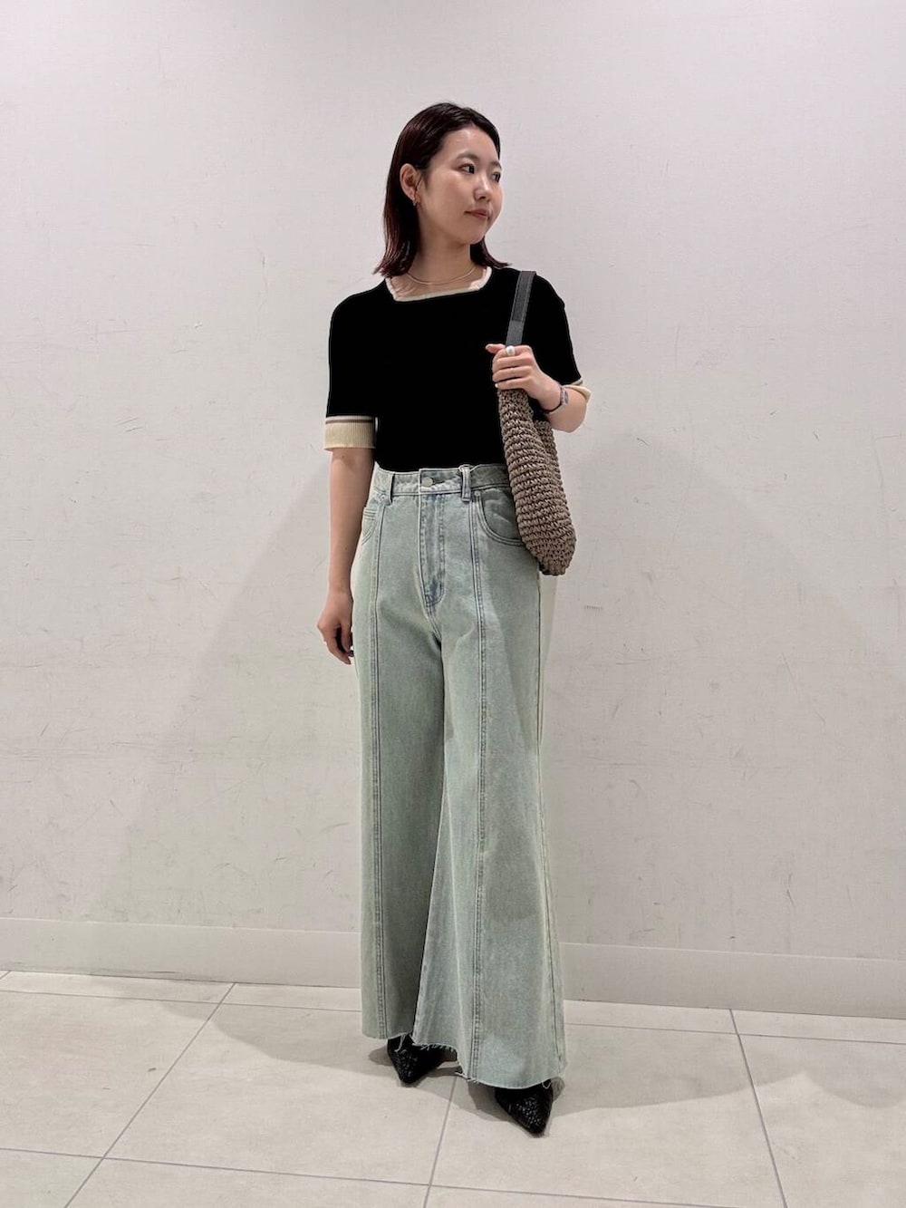 グレー系のトートバッグ、ブラック系のサンダル、ブラック系のニット/セーターを着用したレディースの春コーディネートの3枚目の写真