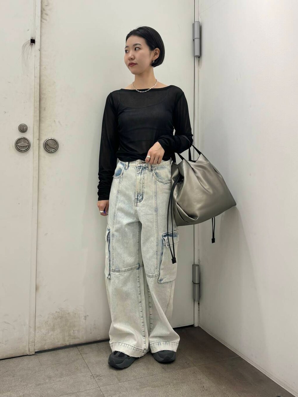 シルバー系のトートバッグ、ブラック系のその他トップス、ブルー系のデニムパンツを着用したレディースの秋コーディネートの3枚目の写真