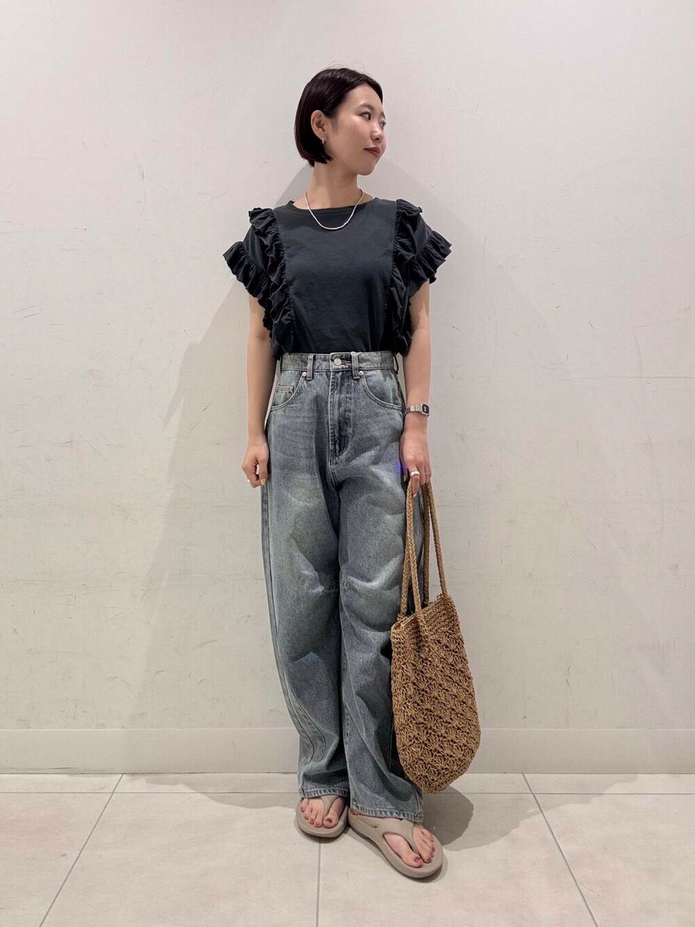 ベージュ系のトートバッグ、ブルー系のデニムパンツ、グレー系のTシャツ/カットソーを着用したレディースの夏コーディネートの3枚目の写真