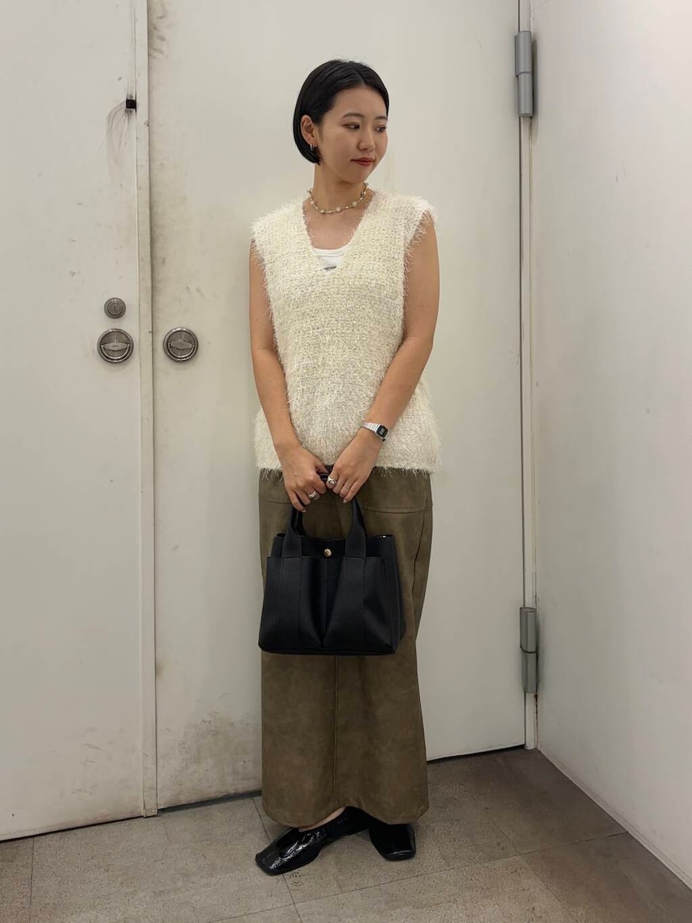 ブラック系のトートバッグ、レッド系のバレエシューズ、グリーン系のスカートを着用したレディースの秋コーディネートの2枚目の写真