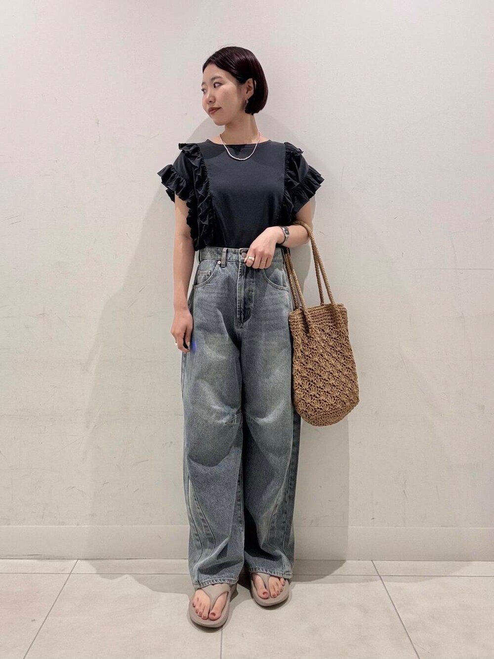 ベージュ系のトートバッグ、ブルー系のデニムパンツ、グレー系のTシャツ/カットソーを着用したレディースの夏コーディネートの2枚目の写真