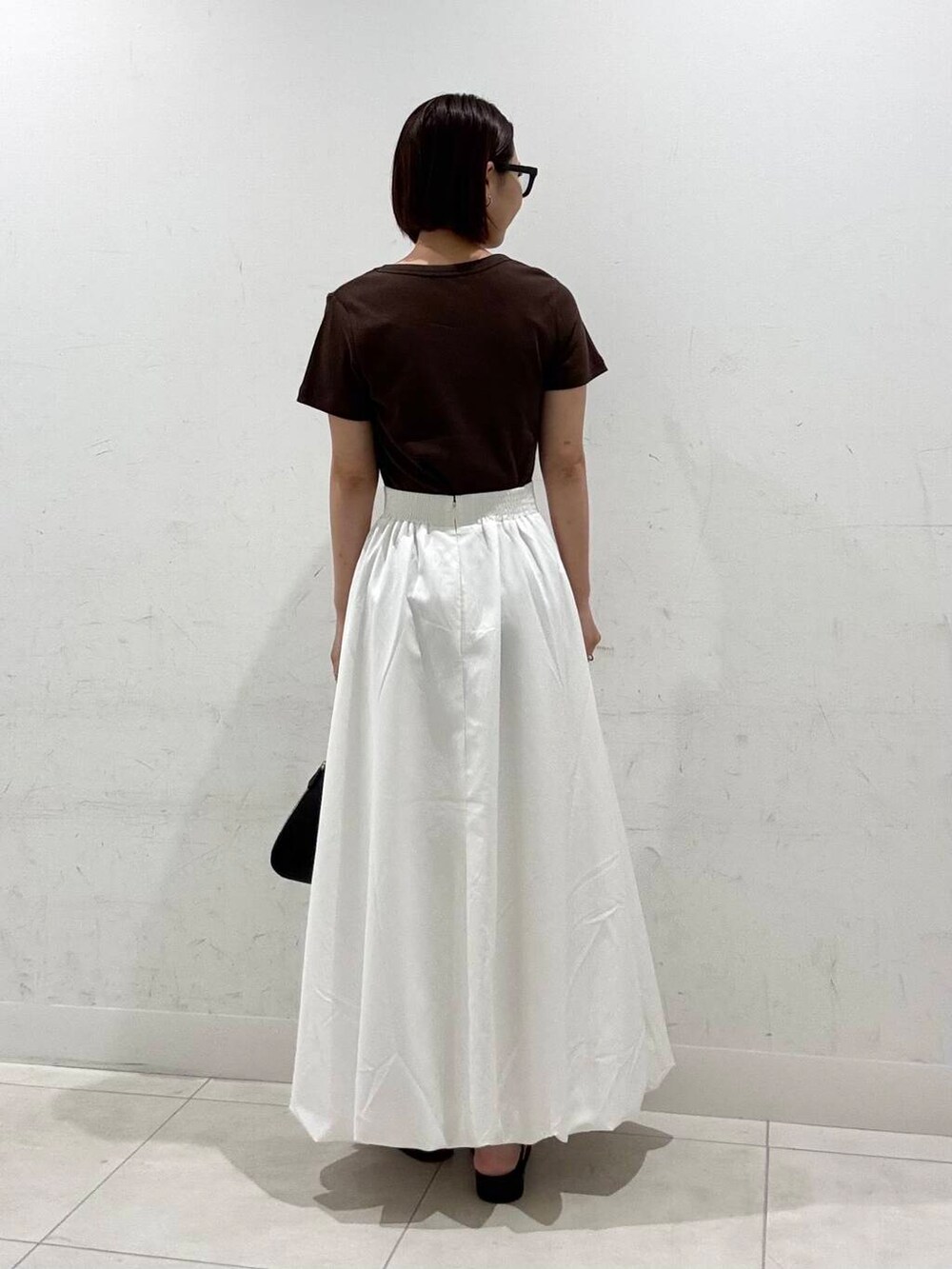 ホワイト系のスカート、ブラック系のハンドバッグ、グレー系のサンダルを着用したレディースの夏コーディネートの4枚目の写真