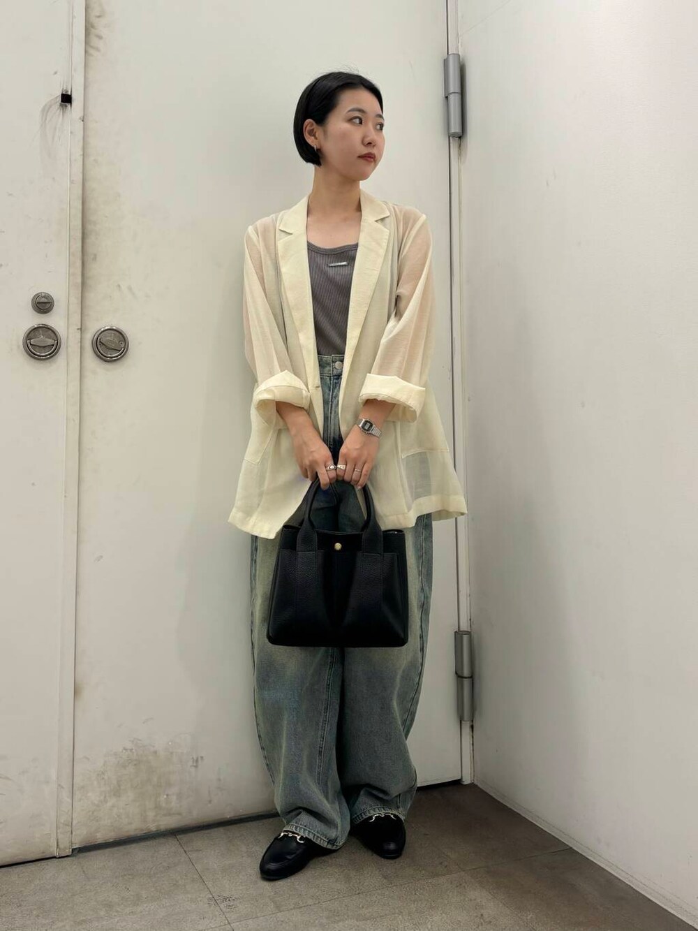 ブラック系のローファー、ブラック系のトートバッグ、ブルー系のデニムパンツを着用したレディースの秋コーディネートの3枚目の写真