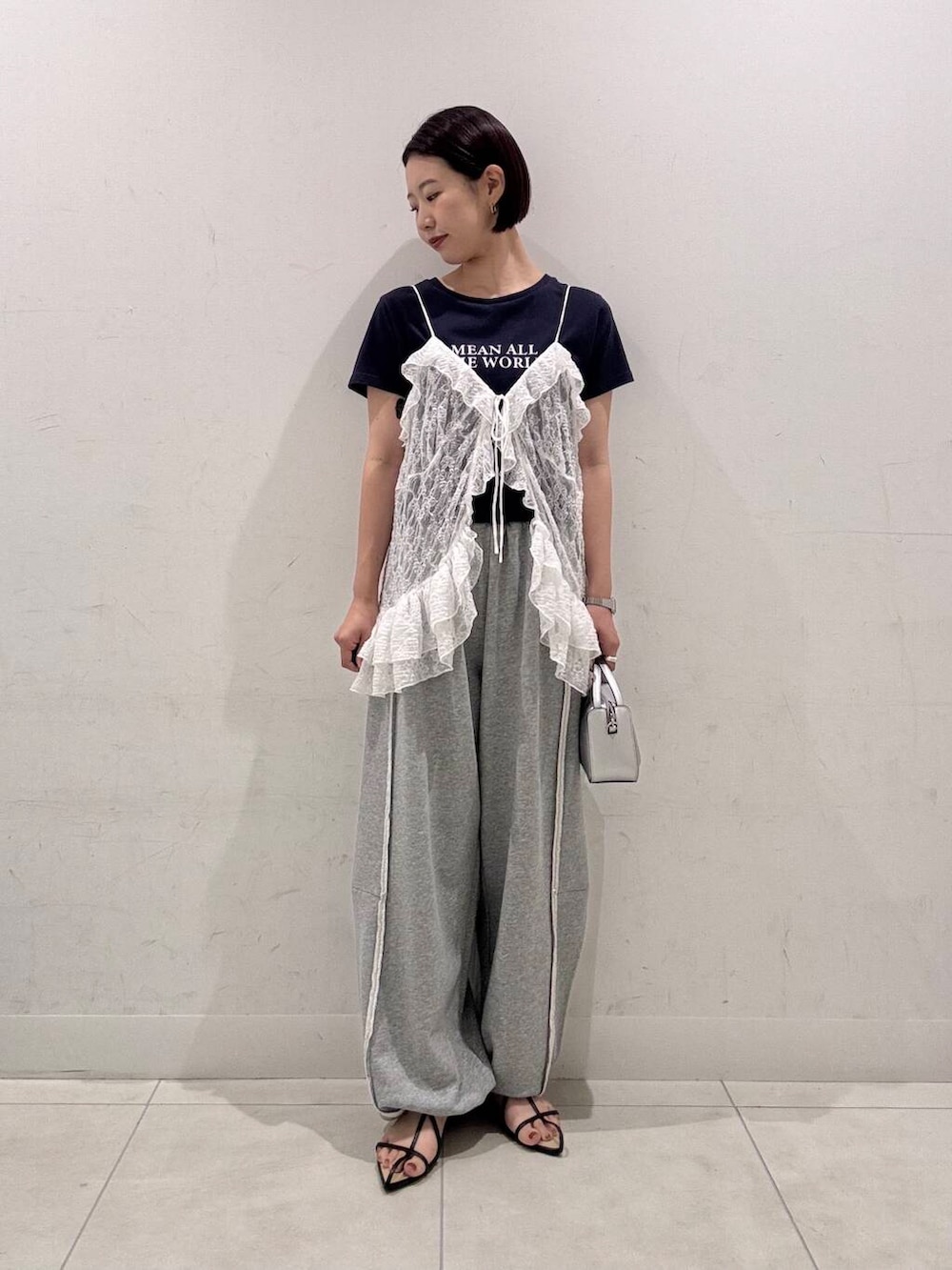 シルバー系のハンドバッグ、ブラック系のサンダル、その他のTシャツ/カットソーを着用したレディースの夏コーディネートの2枚目の写真