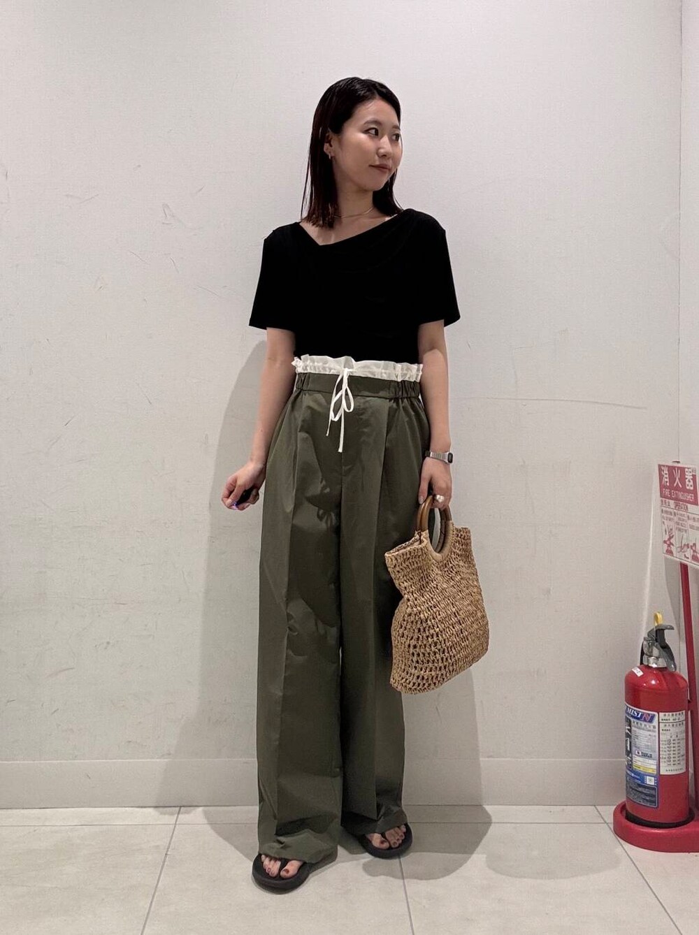ベージュ系のトートバッグ、グリーン系のその他パンツ、ブラック系のTシャツ/カットソーを着用したレディースの夏コーディネートの2枚目の写真