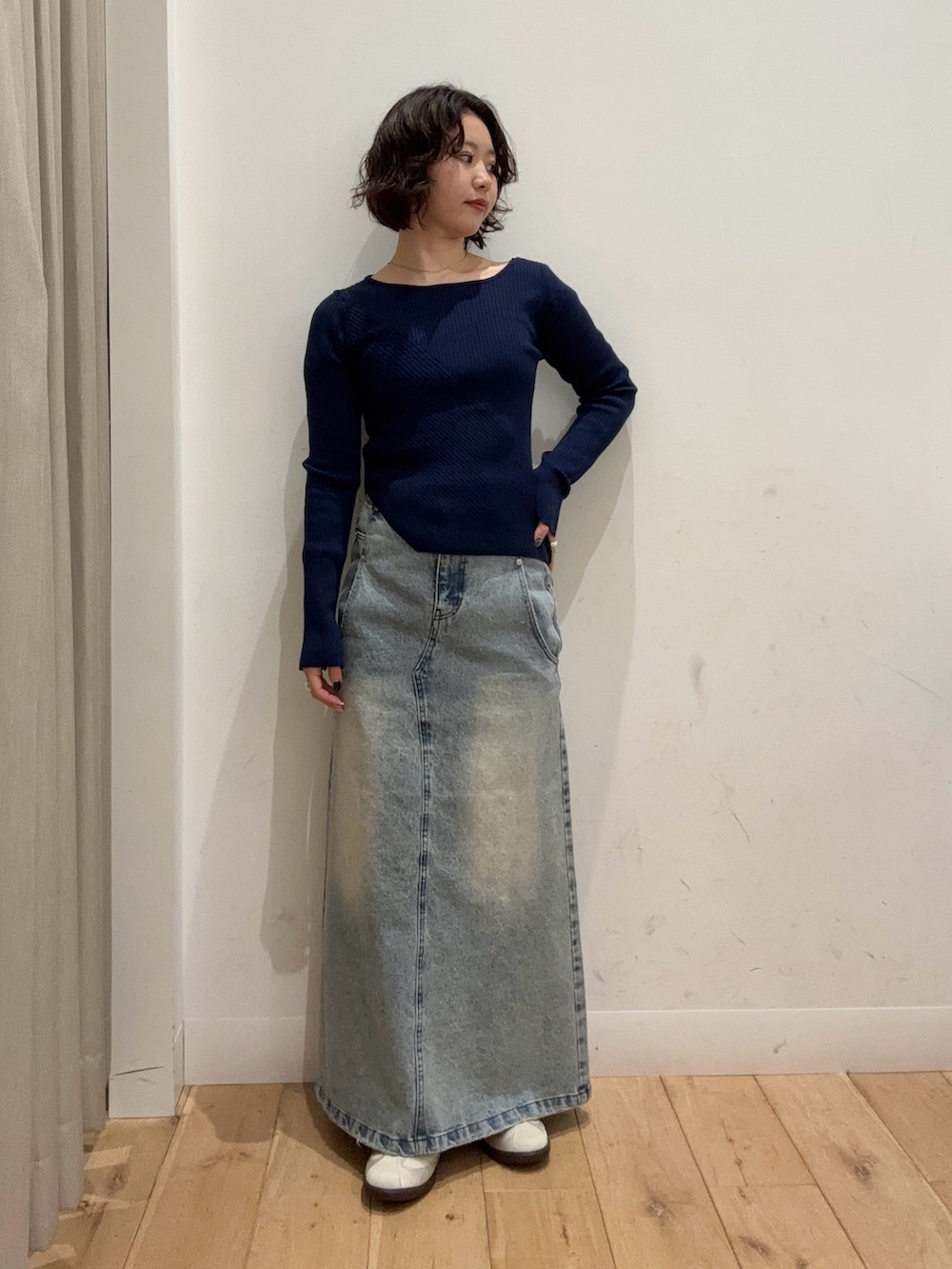 ブルー系のニット/セーター、ブルー系のスカート、ベージュ系のショルダーバッグを着用したレディースの冬コーディネートの2枚目の写真