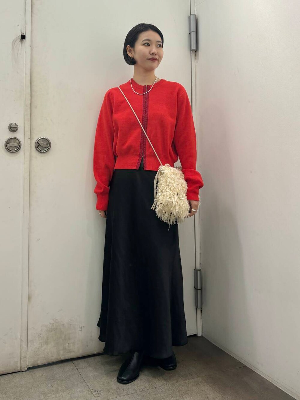 ホワイト系のハンドバッグ、ブラック系のブーツ、ブラック系のスカートを着用したレディースの秋コーディネートの3枚目の写真