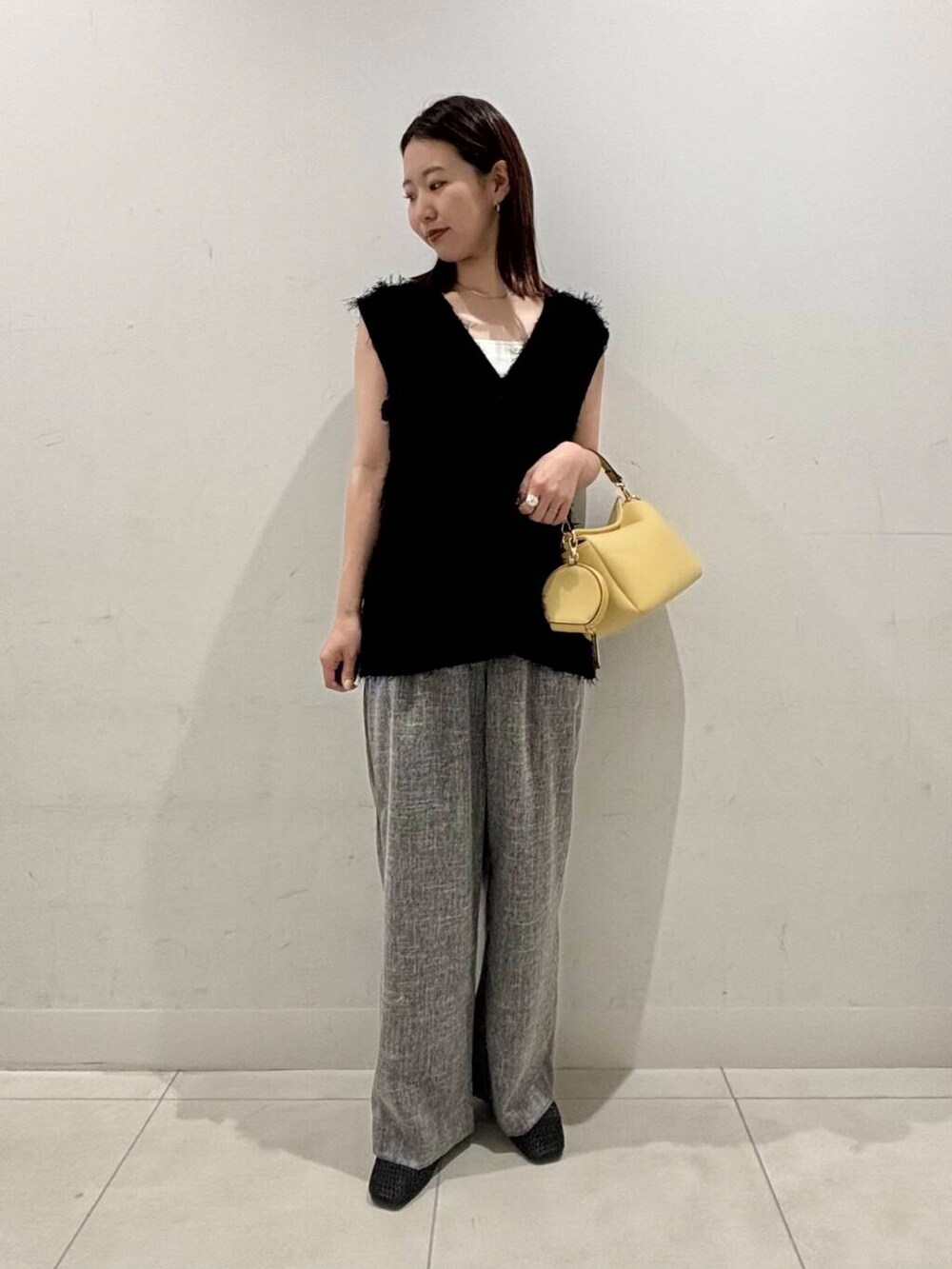 イエロー系のショルダーバッグ、ホワイト系のキャミソール、ブラック系のバレエシューズを着用したレディースの夏コーディネートの3枚目の写真