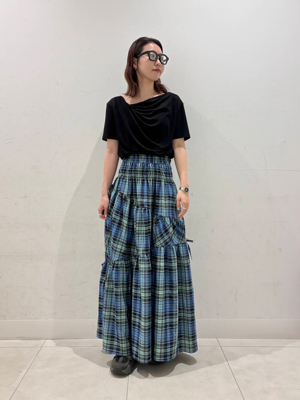 ブルー系のスカート、ブラック系のTシャツ/カットソー、ブラック系のメガネを着用したレディースの夏コーディネートの2枚目の写真