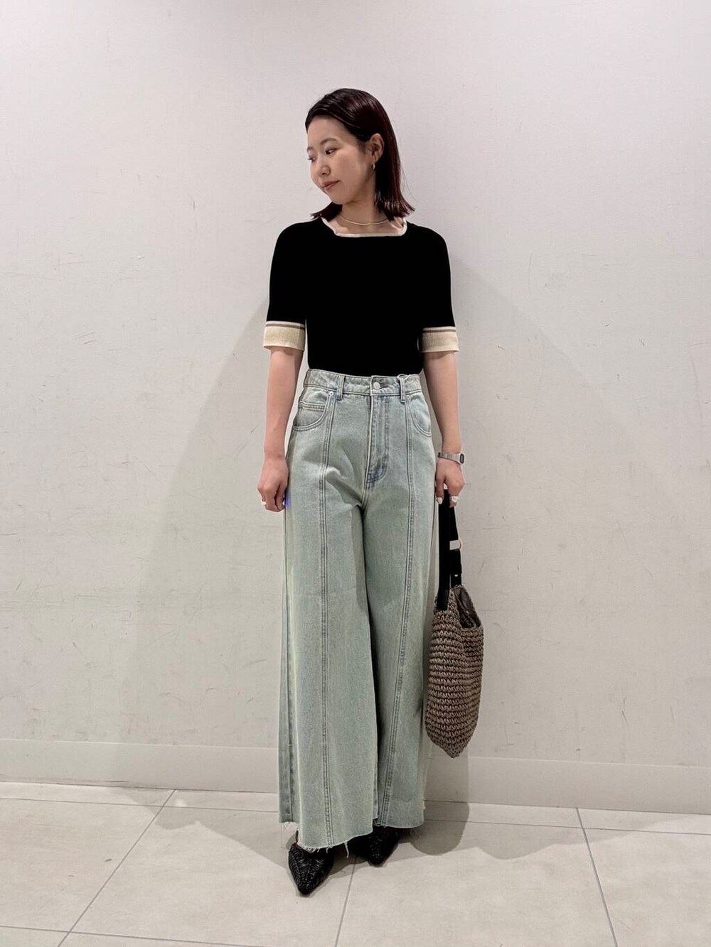 グレー系のトートバッグ、ブラック系のサンダル、ブラック系のニット/セーターを着用したレディースの春コーディネートの2枚目の写真