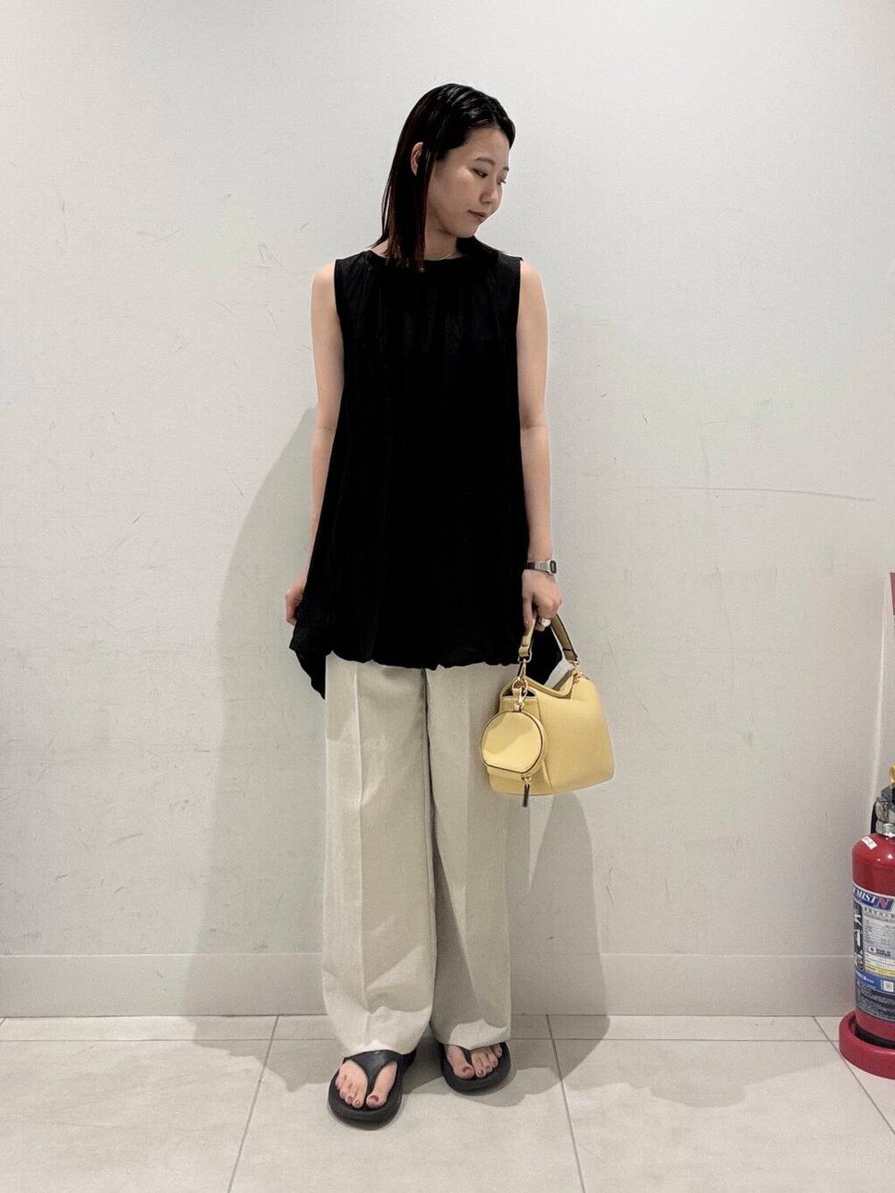 イエロー系のショルダーバッグ、ベージュ系のその他パンツ、ブラック系のシャツ/ブラウスを着用したレディースの春コーディネートの2枚目の写真