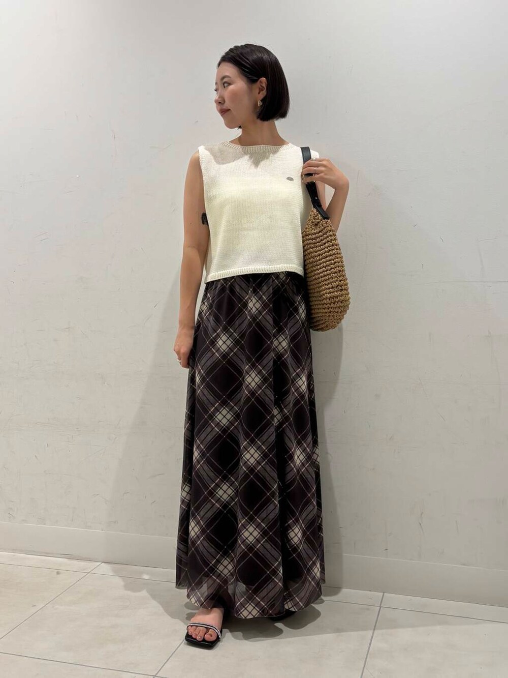 イエロー系のトートバッグ、ブラック系のキャミソール、ブラック系のサンダルを着用したレディースの夏コーディネートの3枚目の写真