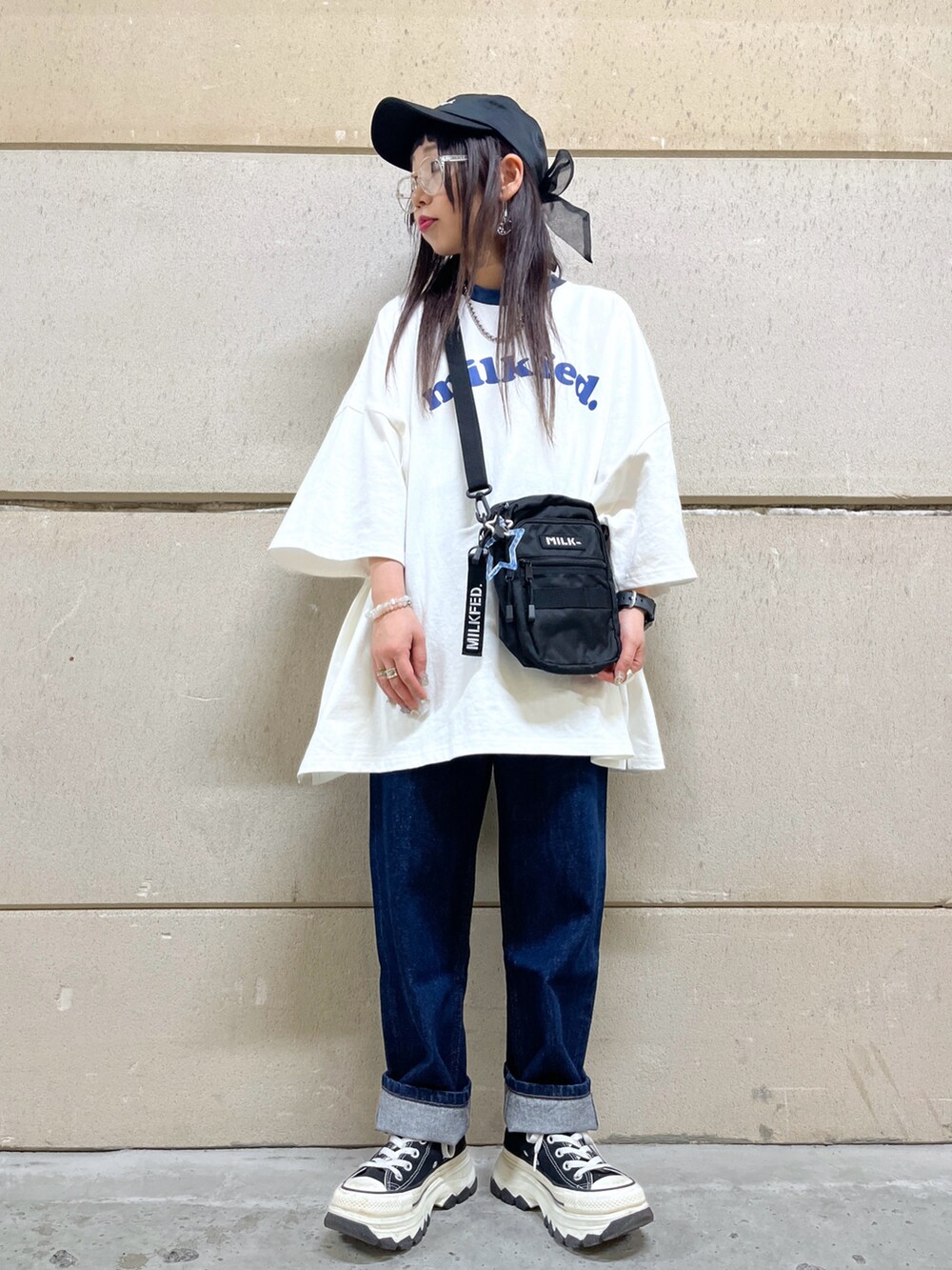 ブルー系のデニムパンツ、ブラック系のショルダーバッグ、ホワイト系のTシャツ/カットソーを着用したレディースの春コーディネートの2枚目の写真