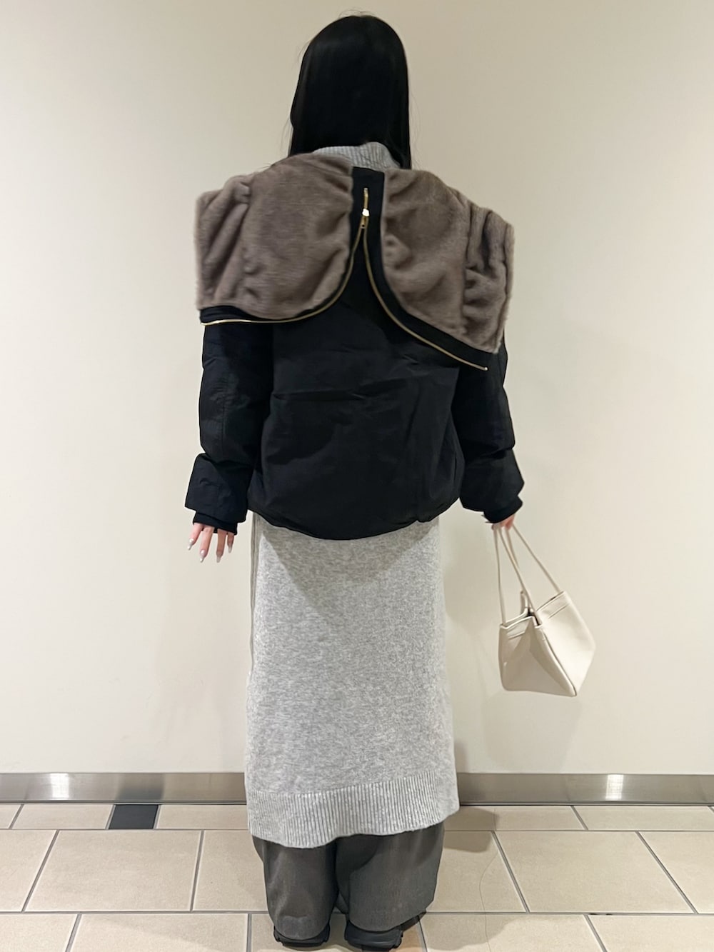 ブラック系のブルゾン、ホワイト系のハンドバッグ、グレー系のその他パンツを着用したレディースの冬コーディネートの3枚目の写真