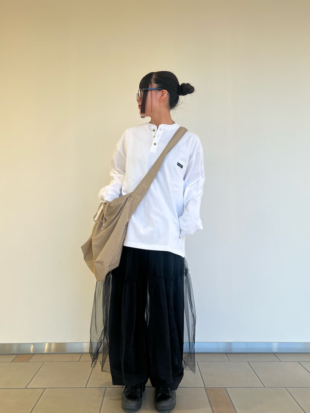ベージュ系のショルダーバッグ、ブラック系のチノパンツ、ブラック系のワンピースを着用したレディースの秋コーディネートの3枚目の写真