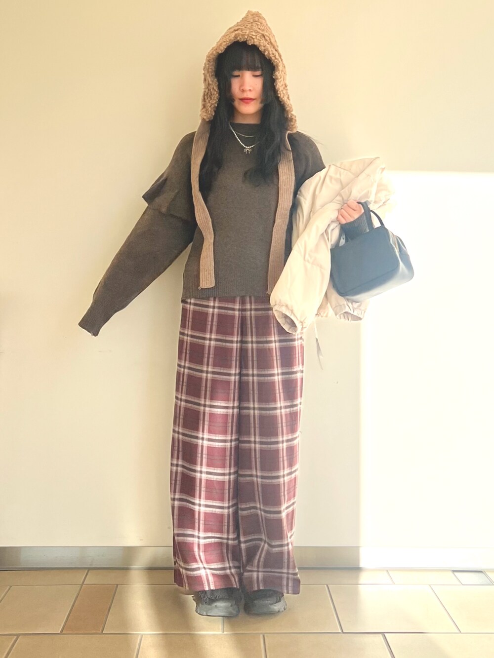 グレー系のダウンジャケット/コート、ブラウン系のニット/セーター、レッド系のその他パンツを着用したレディースの冬コーディネートの4枚目の写真