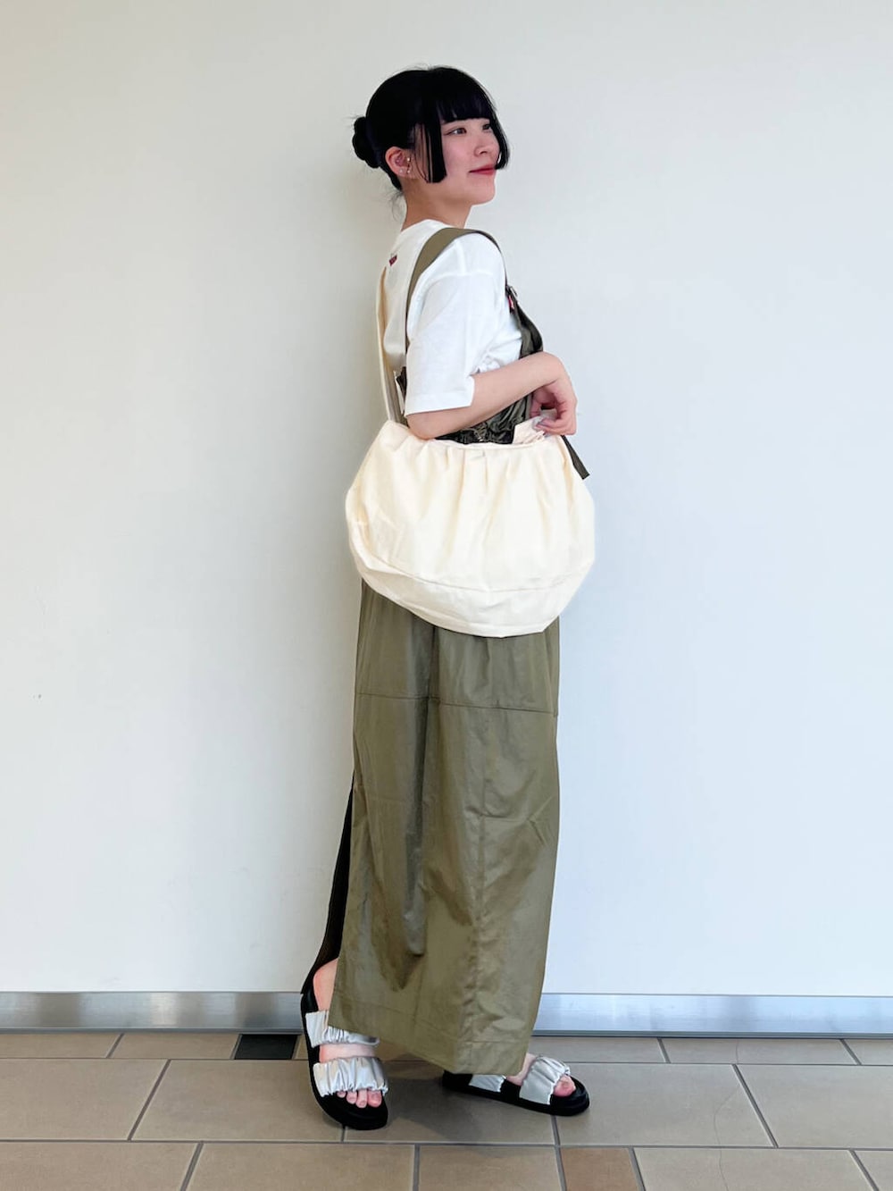 グレー系のサンダル、ホワイト系のショルダーバッグ、グリーン系のワンピースを着用したレディースの夏コーディネートの2枚目の写真