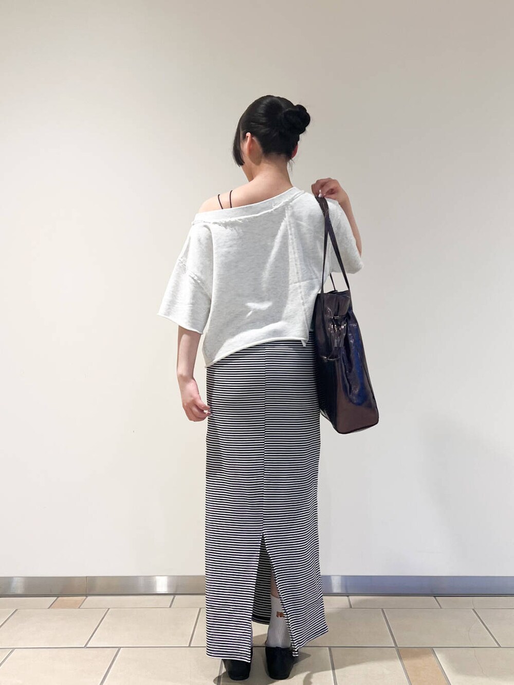 グレー系のトートバッグ、ブラック系のパンプス、ホワイト系のワンピースを着用したレディースの夏コーディネートの3枚目の写真