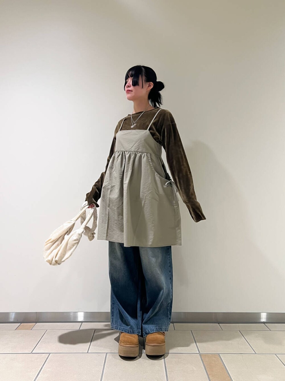 ベージュ系のハンドバッグ、ブルー系のデニムパンツ、ベージュ系のキャミソールを着用したレディースの春コーディネートの2枚目の写真