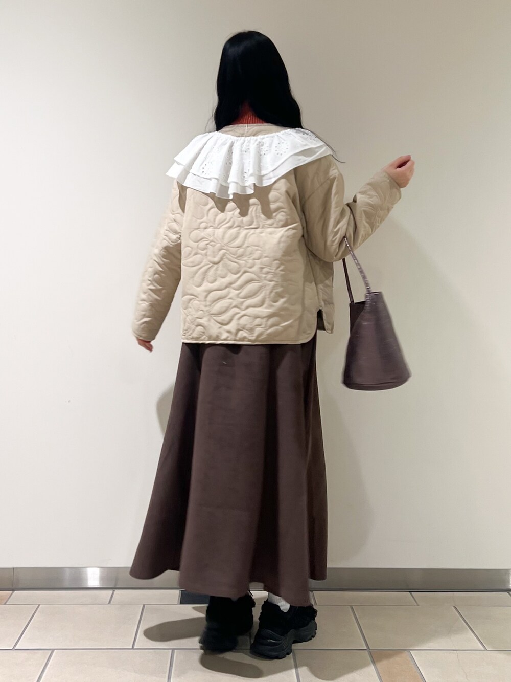 ブラウン系のスカート、ベージュ系のノーカラージャケット、オレンジ系のニット/セーターを着用したレディースの秋コーディネートの2枚目の写真
