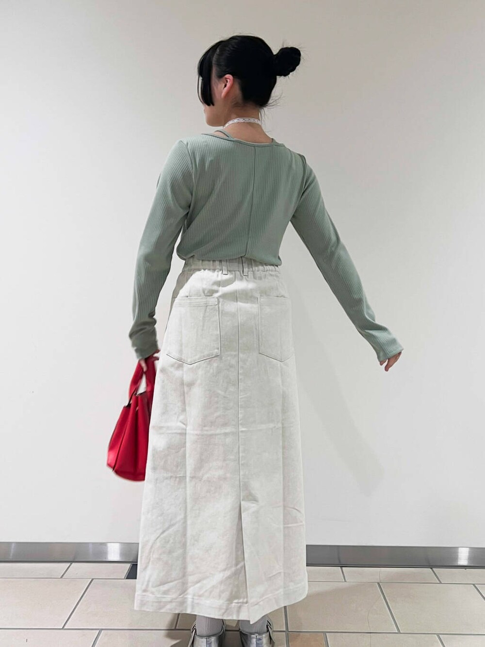 レッド系のトートバッグ、グリーン系のTシャツ/カットソー、ホワイト系のスカートを着用したレディースの春コーディネートの3枚目の写真