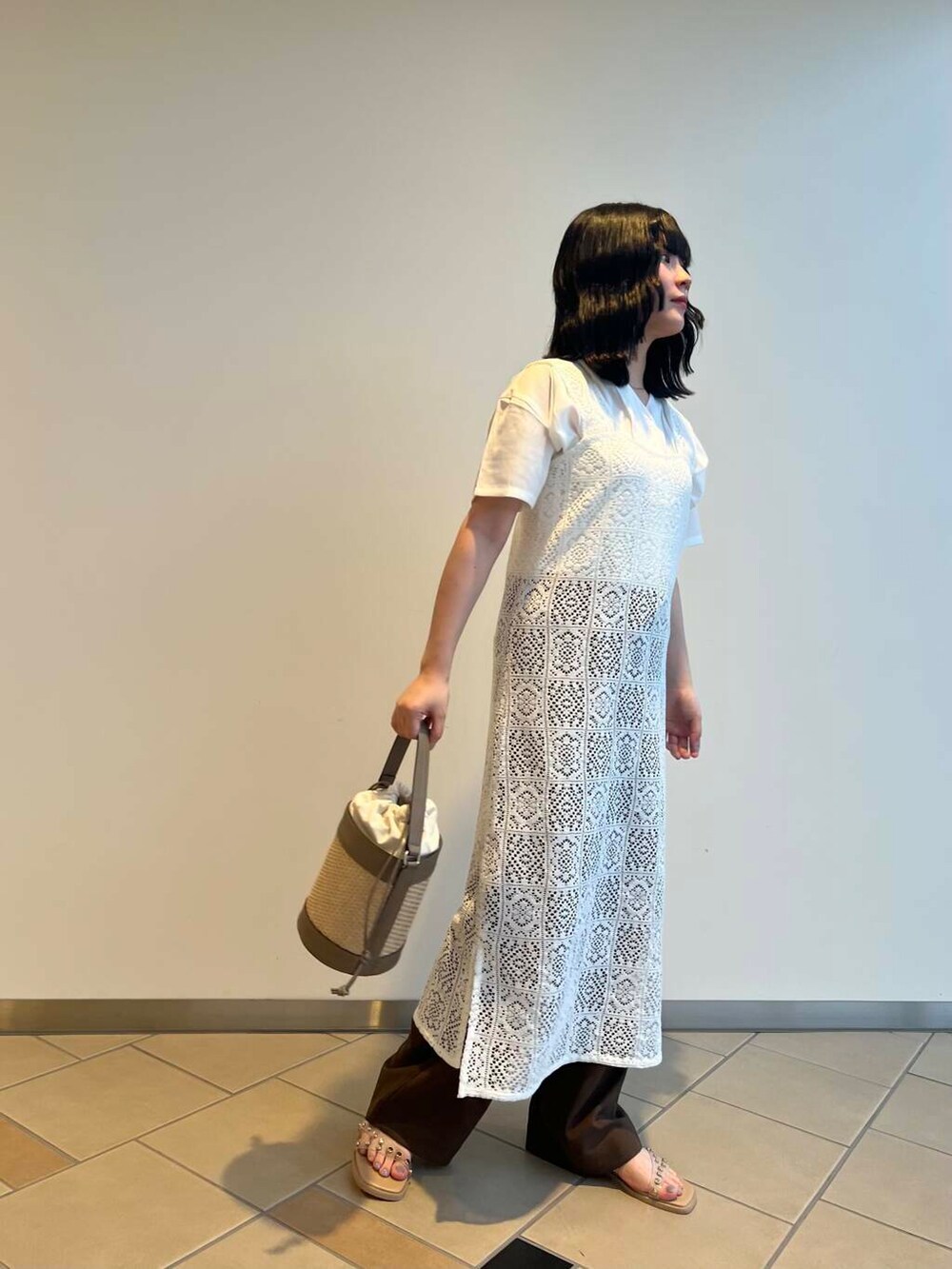 グレー系のショルダーバッグ、ベージュ系のサンダル、ホワイト系のTシャツ/カットソーを着用したレディースの夏コーディネートの2枚目の写真