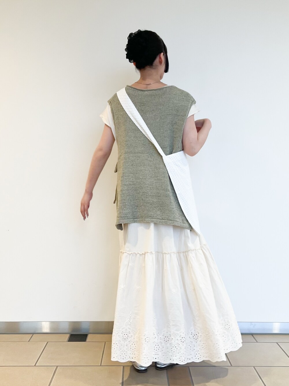 グリーン系のベスト、ホワイト系のワンピースを着用したレディースの夏コーディネートの2枚目の写真