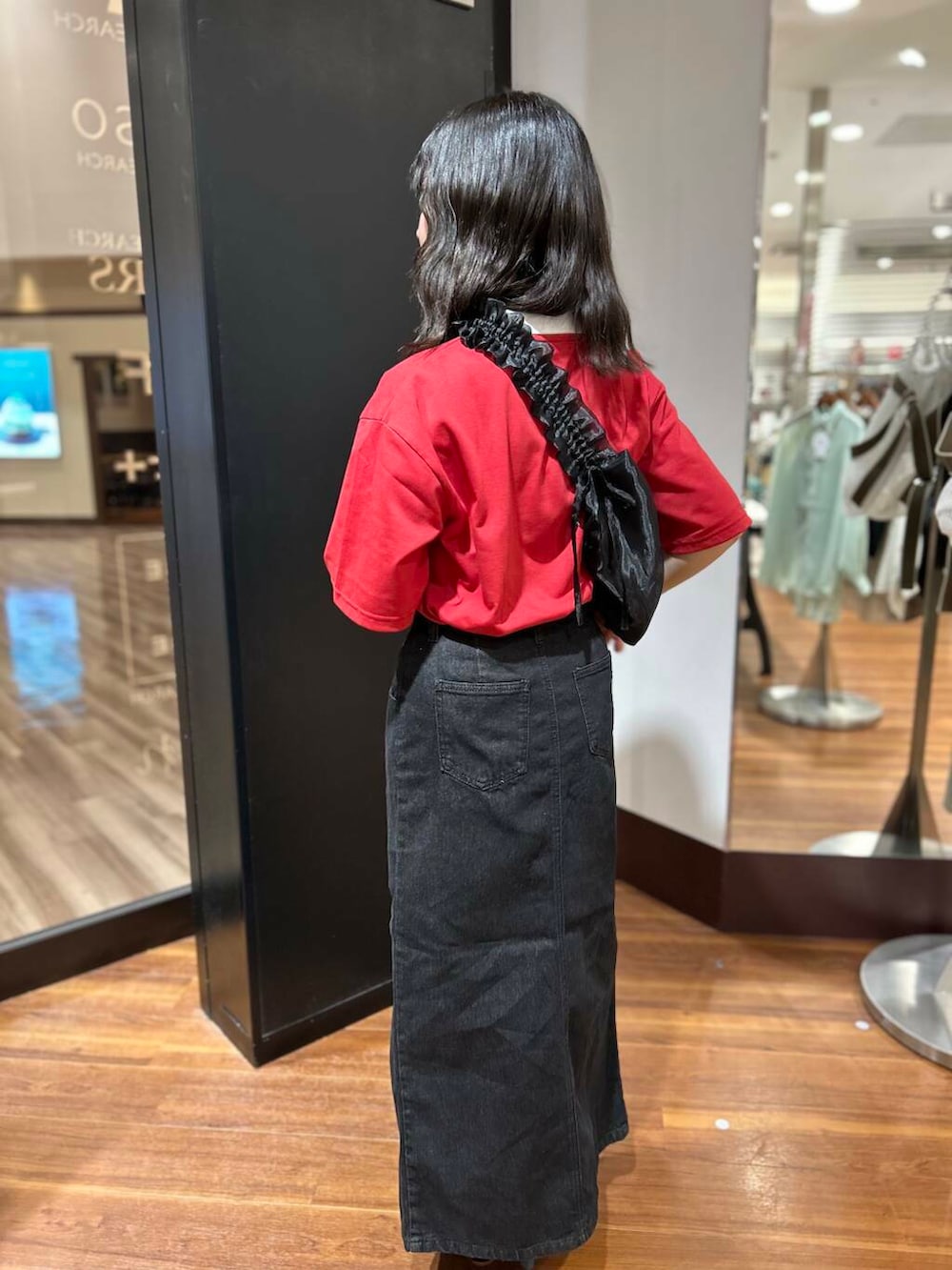 レッド系のTシャツ/カットソー、ブラック系のショルダーバッグ、ブラック系のスカートを着用したレディースの夏コーディネートの2枚目の写真