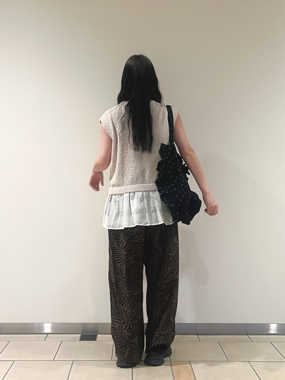 ホワイト系のニット/セーター、ブラウン系のその他パンツ、ブラック系のトートバッグを着用したレディースの夏コーディネートの2枚目の写真