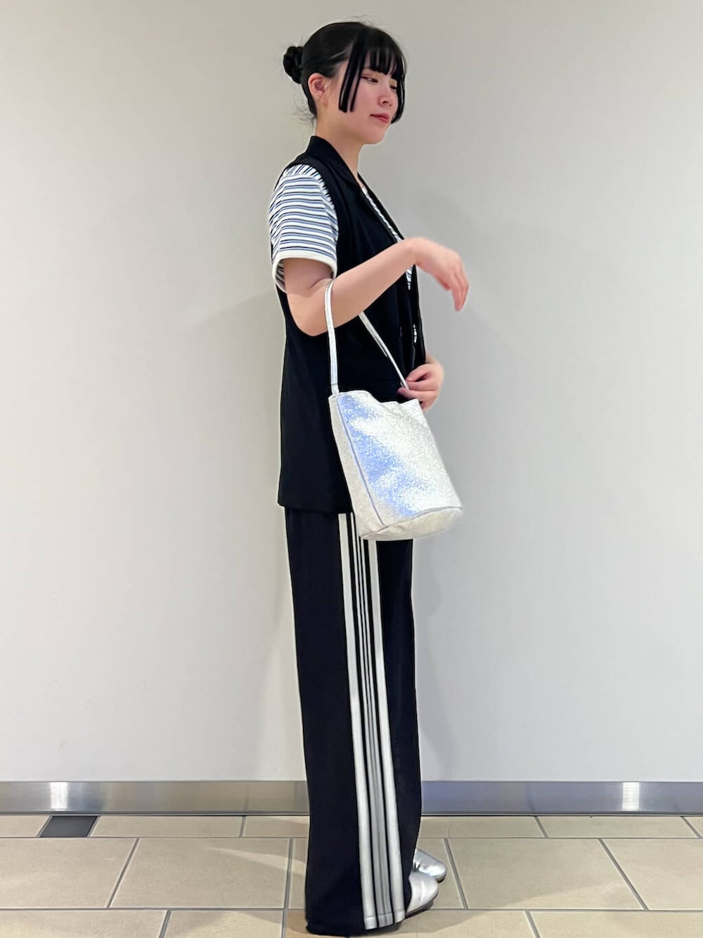 シルバー系のハンドバッグ、ブラック系のベスト、ブルー系のTシャツ/カットソーを着用したレディースの春コーディネートの2枚目の写真