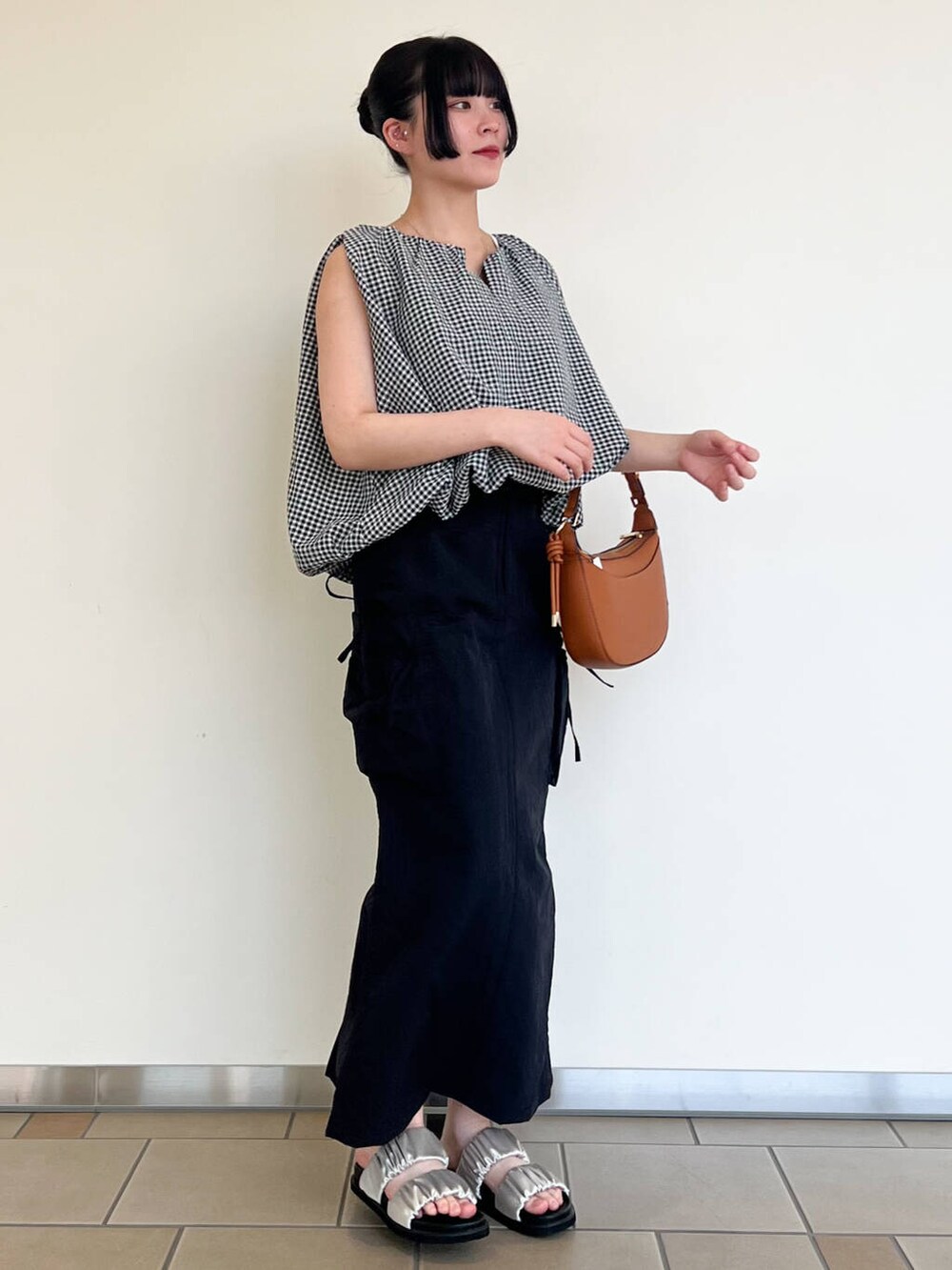 グレー系のサンダル、ブラック系のスカート、ホワイト系のシャツ/ブラウスを着用したレディースの夏コーディネートの2枚目の写真