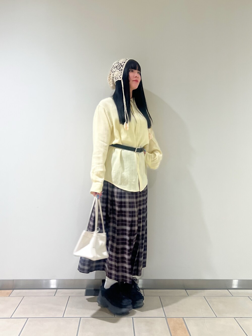 ホワイト系のハンドバッグ、イエロー系のシャツ/ブラウス、ブルー系のスカートを着用したレディースの春コーディネートの2枚目の写真