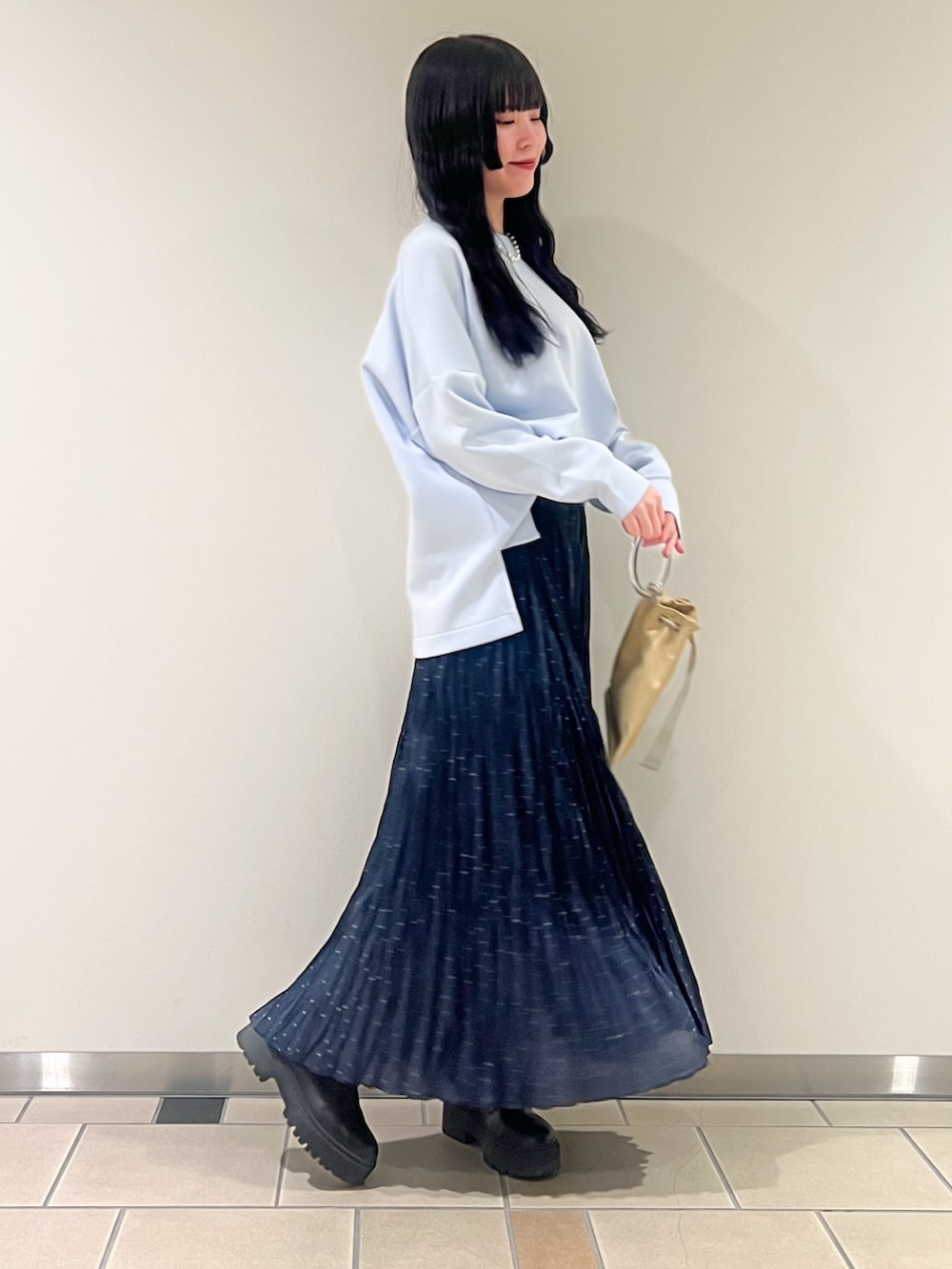 ブルー系のスウェット、イエロー系のショルダーバッグ、シルバー系のネックレスを着用したレディースの冬コーディネートの2枚目の写真