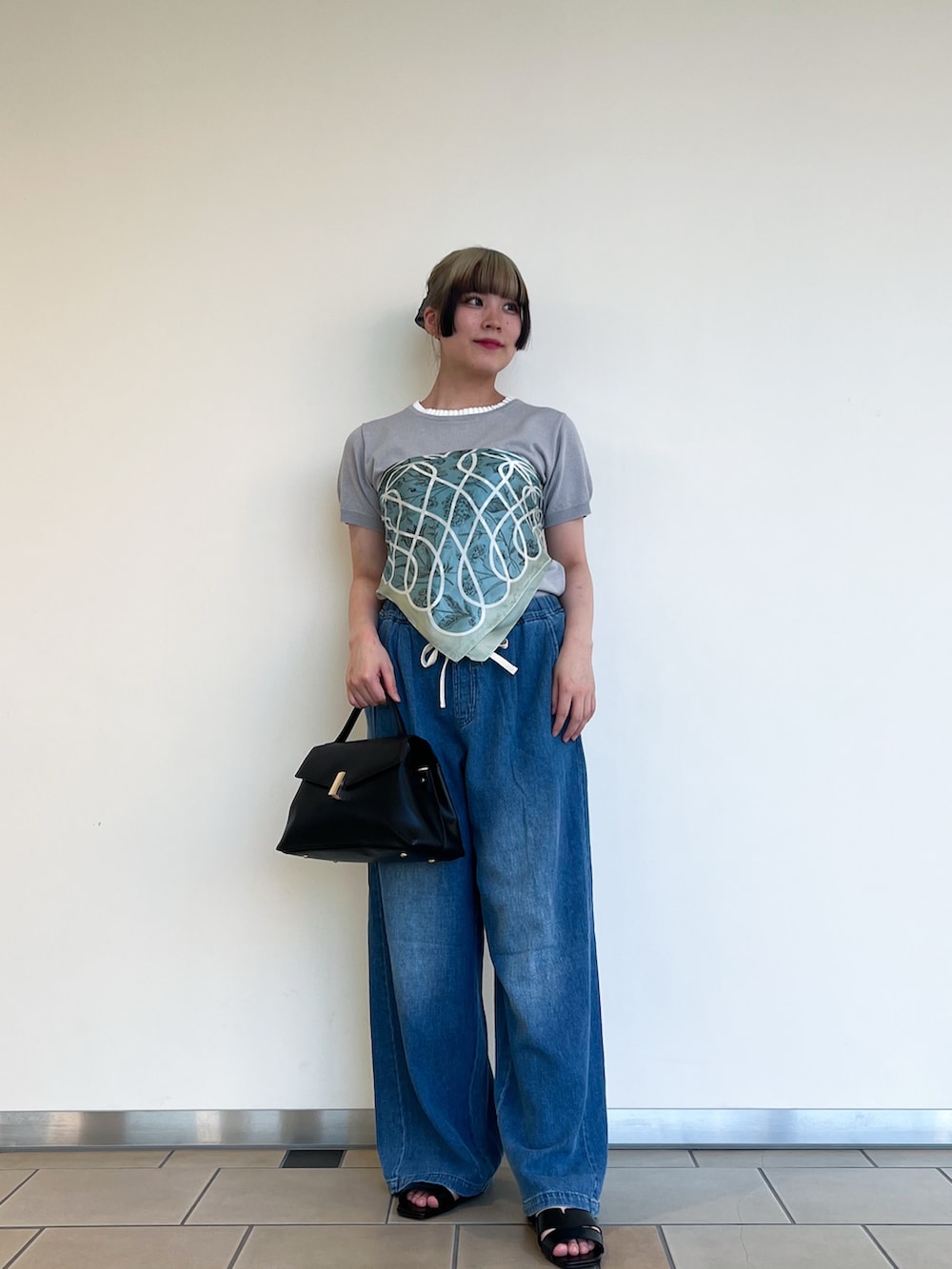 グレー系のニット/セーター、ブルー系のデニムパンツ、ブラック系のハンドバッグを着用したレディースの夏コーディネートの2枚目の写真