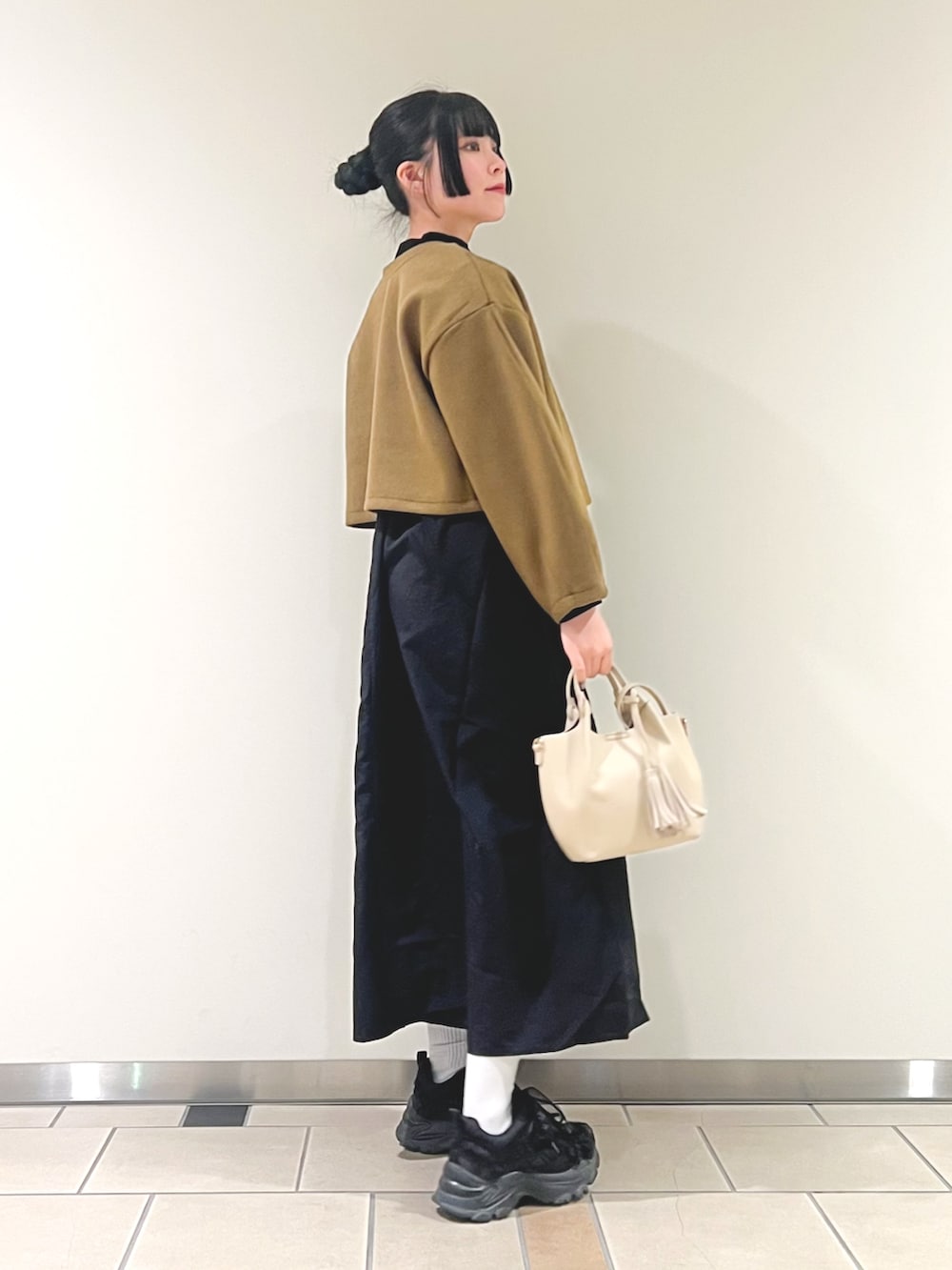 イエロー系のワンピース、ホワイト系のショルダーバッグを着用したレディースの秋コーディネートの3枚目の写真