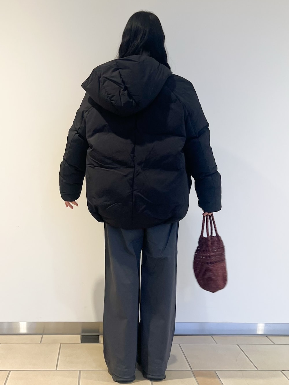 ホワイト系のTシャツ/カットソー、グレー系のニット/セーター、ブラック系のダウンジャケット/コートを着用したレディースの冬コーディネートの4枚目の写真