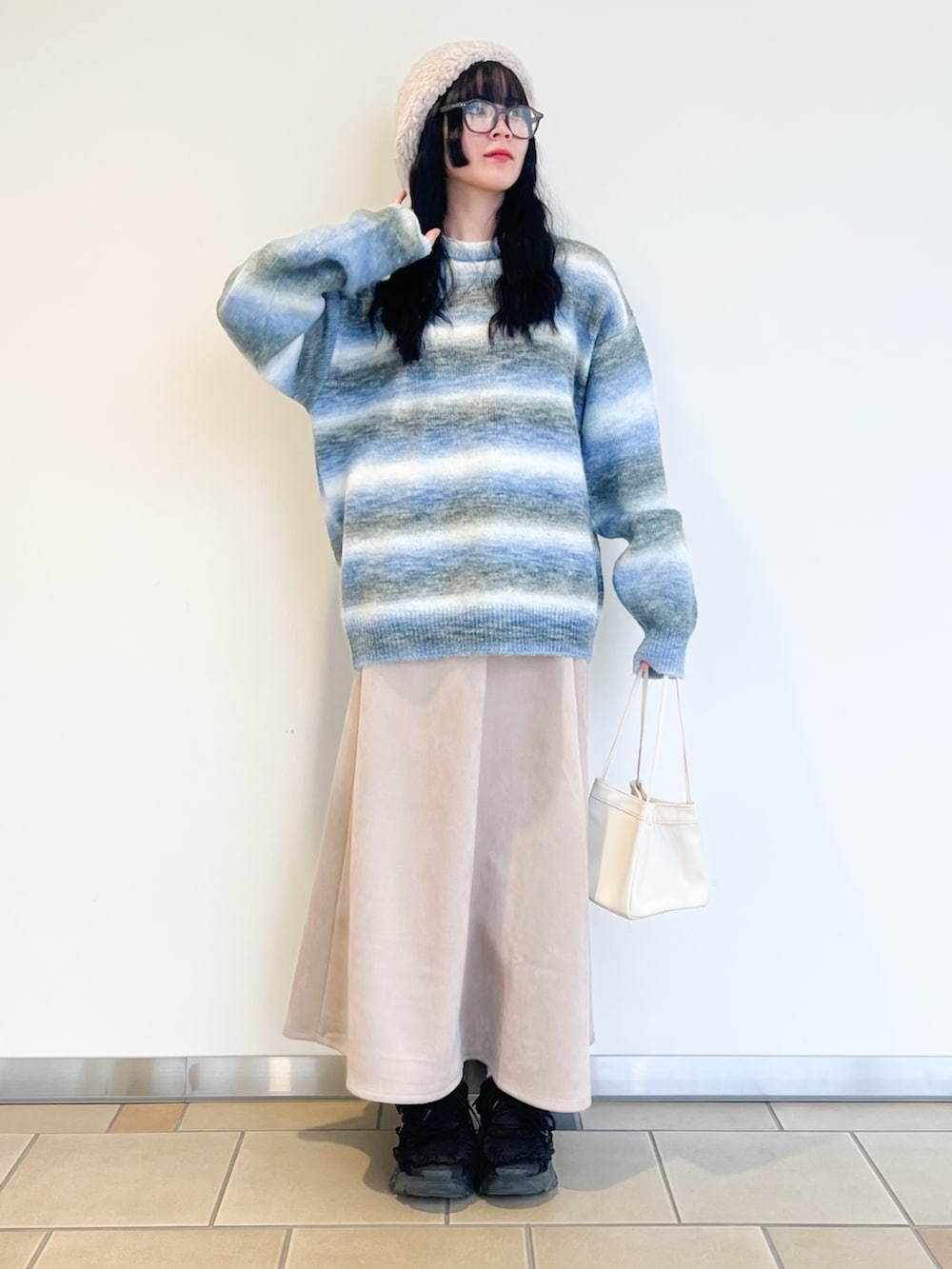 ベージュ系のスカート、ブルー系のニット/セーター、ブラウン系のダウンジャケット/コートを着用したレディースの冬コーディネートの3枚目の写真