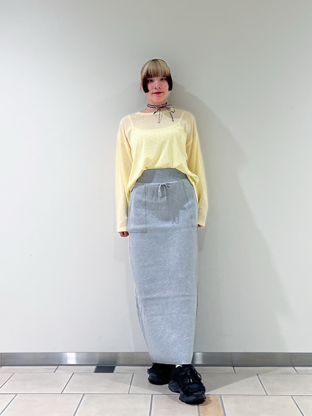 グレー系のスカート、イエロー系のTシャツ/カットソー、ブラック系のネックレスを着用したレディースの夏コーディネートの2枚目の写真