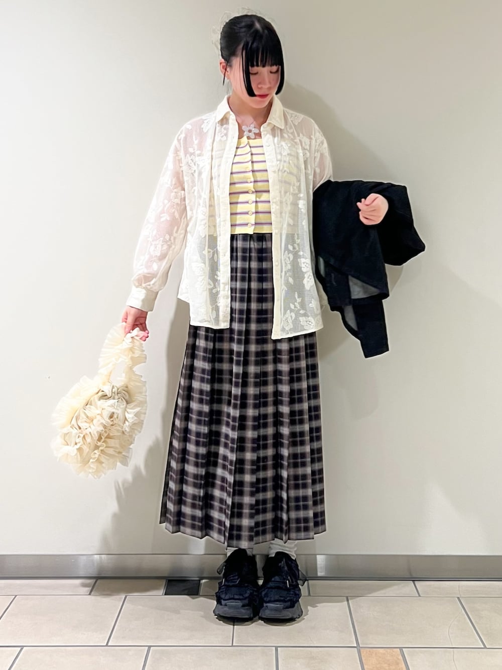 ブラック系のデニムジャケット、イエロー系のニット/セーター、ブルー系のスカートを着用したレディースの春コーディネートの2枚目の写真