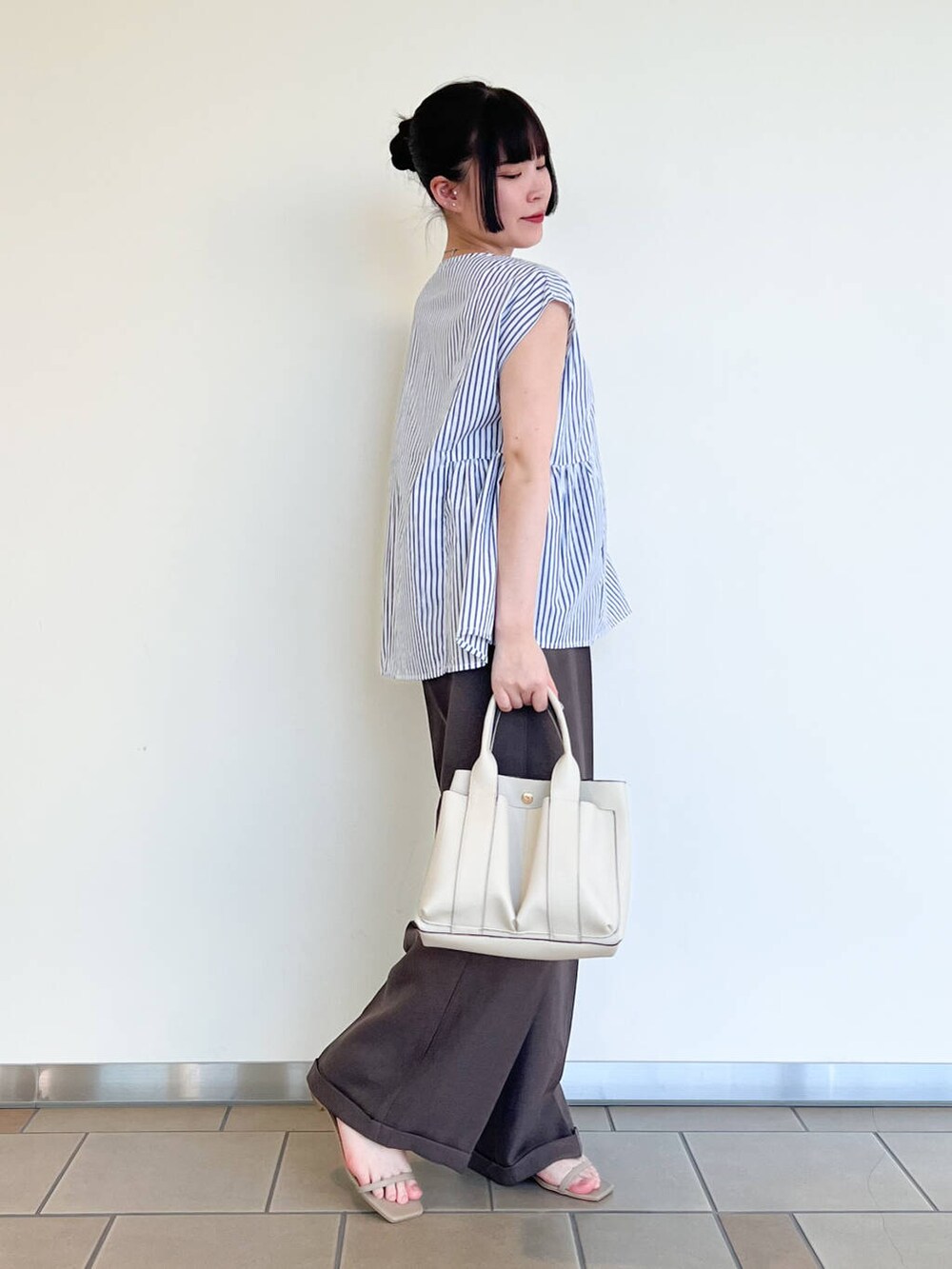 ホワイト系のトートバッグ、グレー系のサンダル、ブラウン系のその他パンツを着用したレディースの夏コーディネートの2枚目の写真