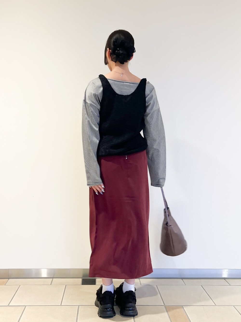 レッド系のスカート、ホワイト系のTシャツ/カットソー、ブラック系のニット/セーターを着用したレディースの秋コーディネートの2枚目の写真