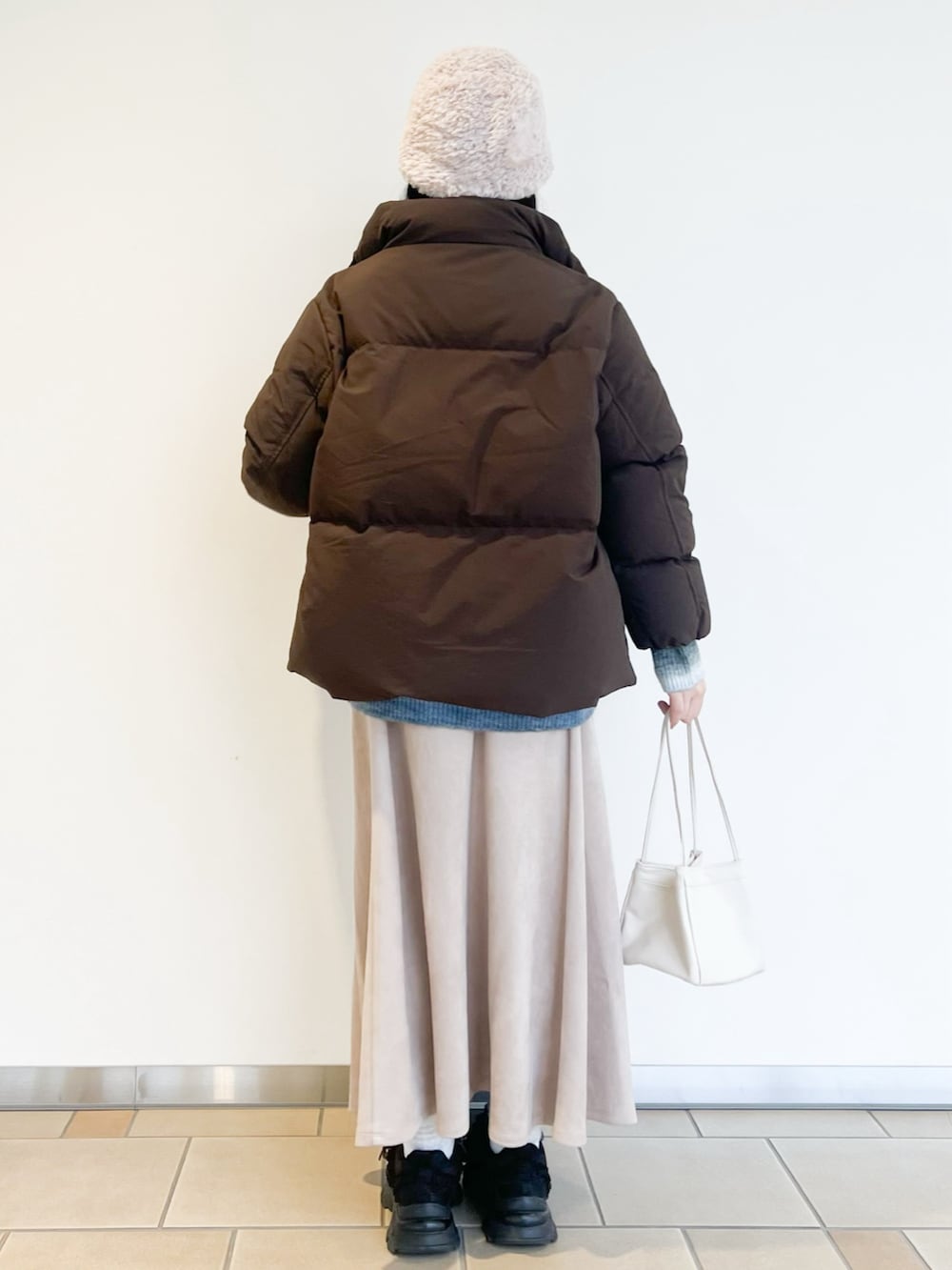 ベージュ系のスカート、ブルー系のニット/セーター、ブラウン系のダウンジャケット/コートを着用したレディースの冬コーディネートの2枚目の写真