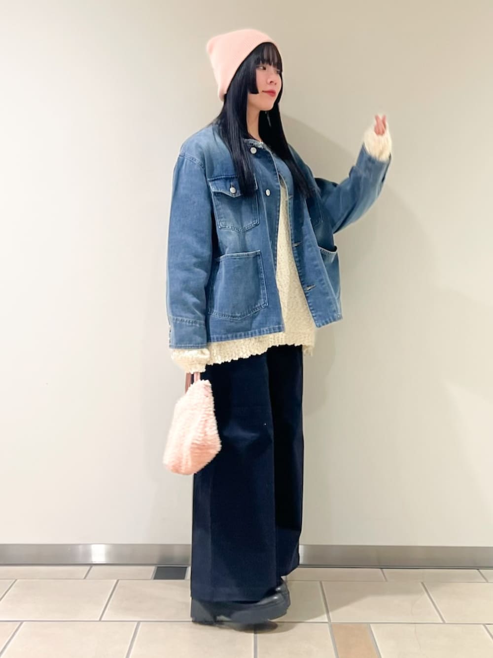 ブルー系のデニムジャケット、ホワイト系のニット/セーター、ピンク系のショルダーバッグを着用したレディースの冬コーディネートの3枚目の写真