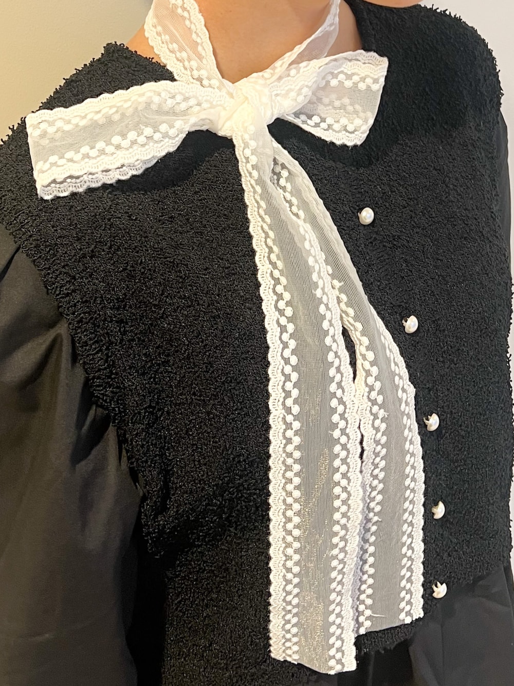 ブルー系のデニムパンツ、ブラック系のチュニック、ホワイト系のハンドバッグを着用したレディースの夏コーディネートの3枚目の写真