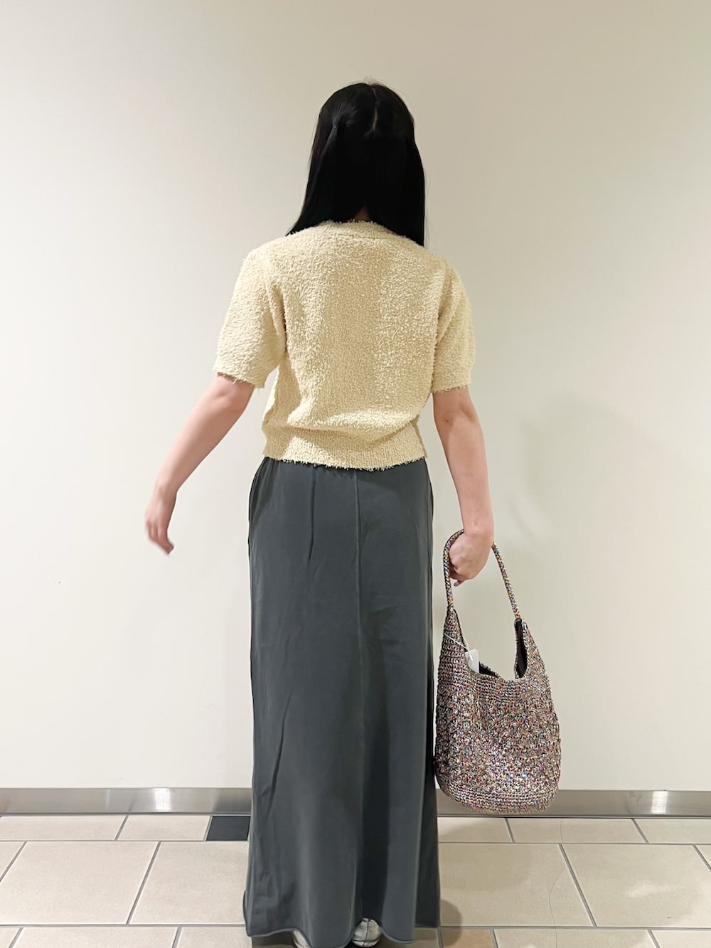 ブラック系のスカート、イエロー系のニット/セーター、その他のハンドバッグを着用したレディースの秋コーディネートの2枚目の写真