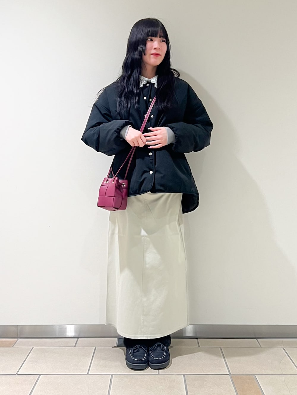 ベージュ系のスカート、グレー系のニット/セーター、ブラック系のダウンジャケット/コートを着用したレディースの冬コーディネートの2枚目の写真