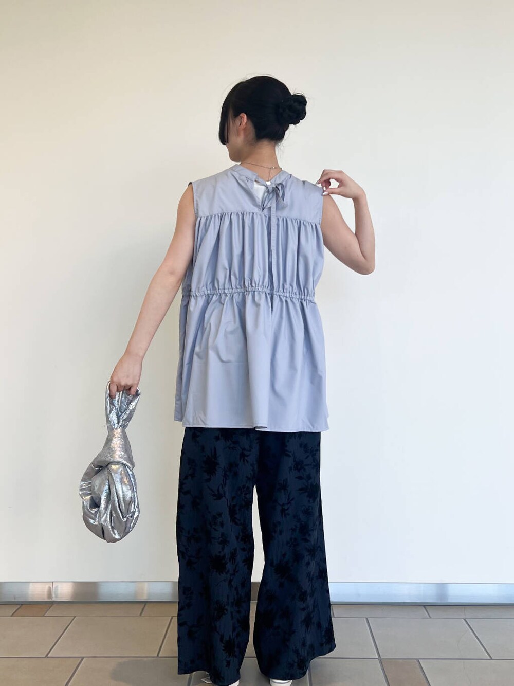 シルバー系のハンドバッグ、シルバー系のサンダル、ブルー系のその他パンツを着用したレディースの夏コーディネートの3枚目の写真