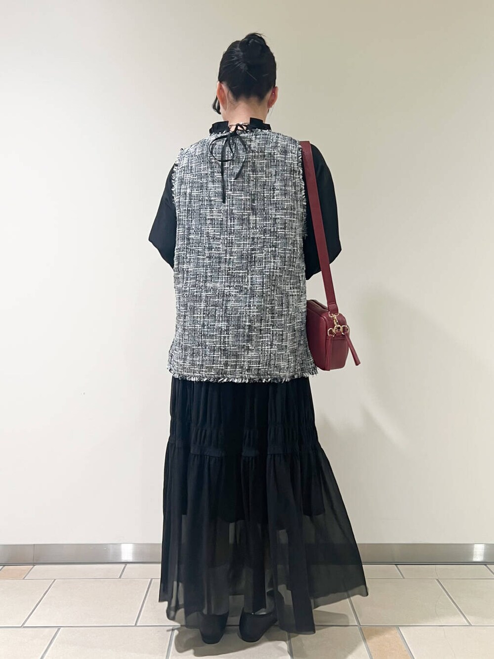 ブラック系のバレエシューズ、レッド系のショルダーバッグ、ブラック系のベストを着用したレディースの春コーディネートの3枚目の写真